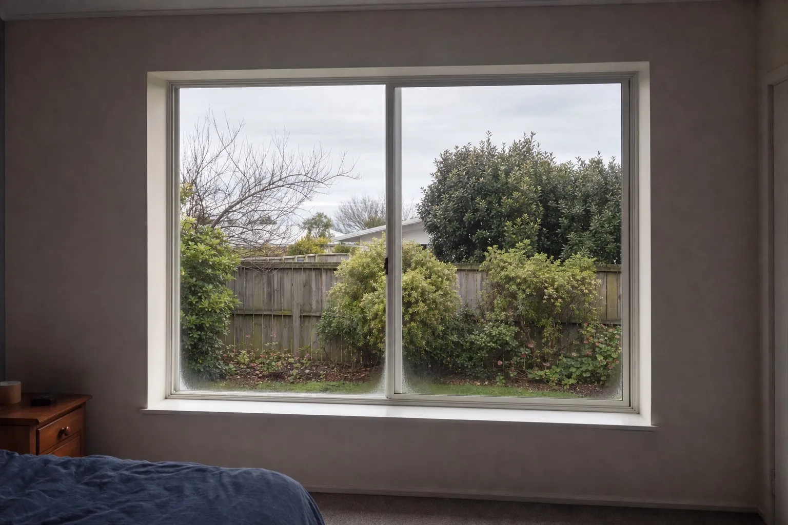 Illustrative: a 1990s plaster-reveal window with an aluminium frame and misting at the corners